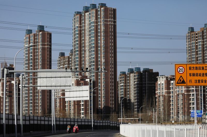 © Reuters. People ride scooters past residential buildings in Beijing