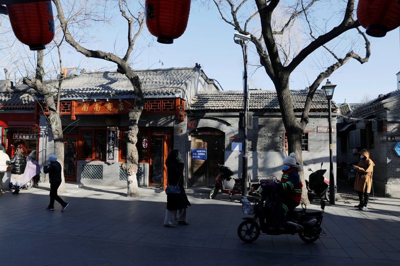 &copy; Reuters. People wearing protective masks walk along Nanluoguxiang alley following the coronavirus disease (COVID-19) outbreak in Beijing
