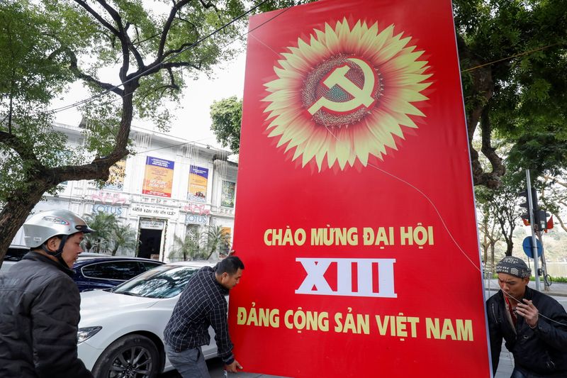 © Reuters. Workers set up a poster for upcoming 13th National Congress of the ruling Communist Party of Vietnam, on a street in Hanoi