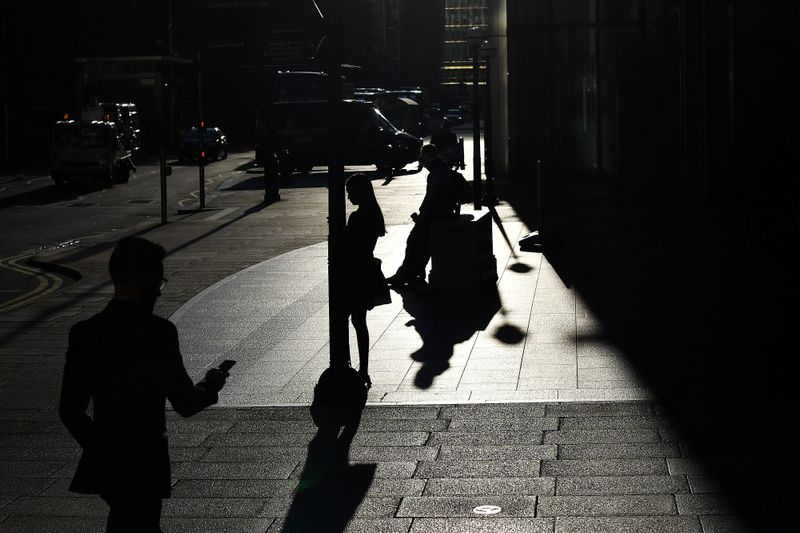 &copy; Reuters. The early morning sun silhouettes commuters as they make their way through Canary Wharf in London