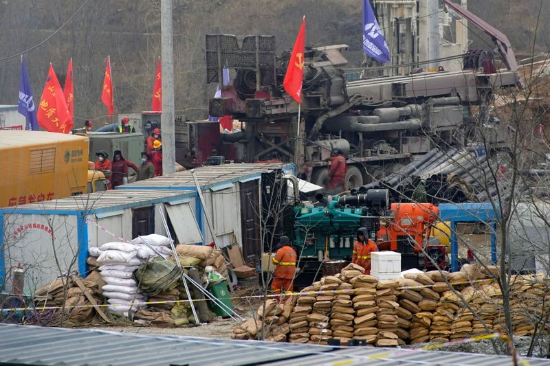 © Reuters. Rescuers work at the Hushan gold mine where workers were trapped underground after the Jauary 10 explosion, in Qixia