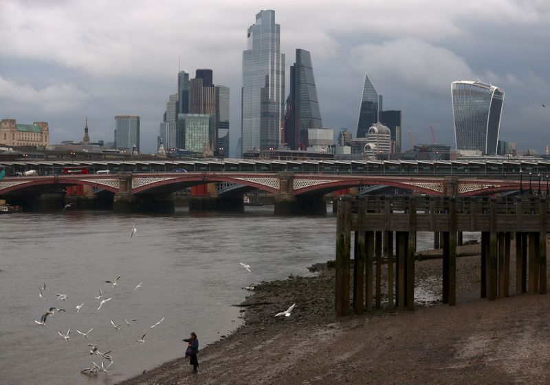 &copy; Reuters. FILE PHOTO: A woman feeds birds on the bank of the river Thames with London&apos;s financial district seen in the background, amid the coronavirus disease (COVID-19) in London