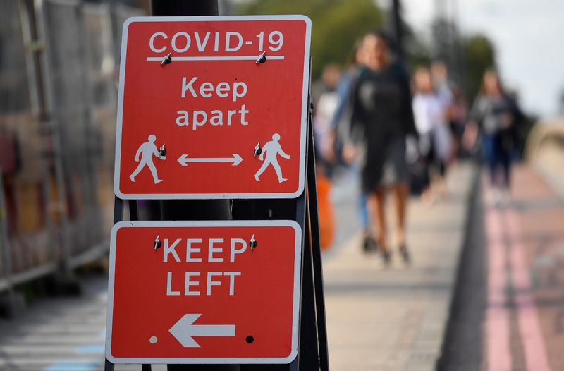 &copy; Reuters. Pedestrians walk near public health signs, whilst the reproduction &quot;R&quot; number of COVID-19 infections in the United Kingdom has risen and may be above 1, London, Britain
