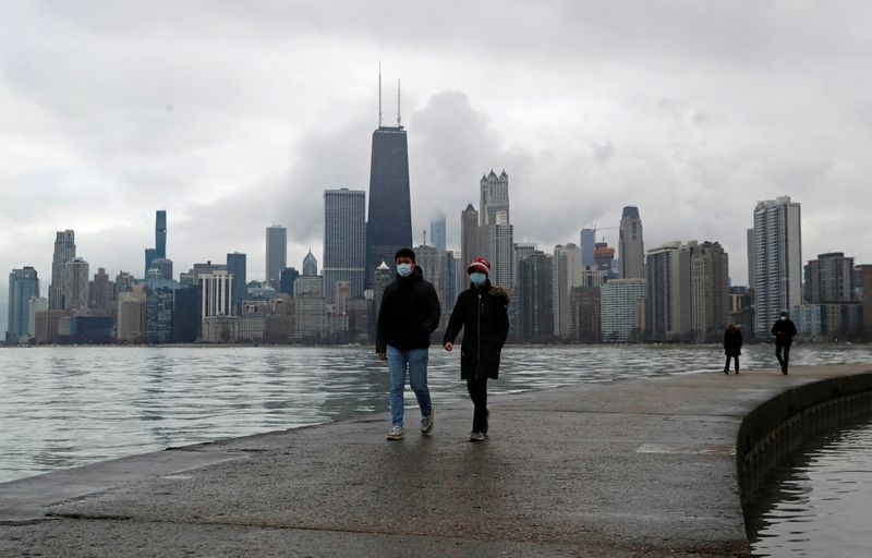 © Reuters. FILE PHOTO: People wearing protective face masks walk, as the global outbreak of the coronavirus disease (COVID-19) continues, along the shores of Lake Michigan in Chicago, Illinois