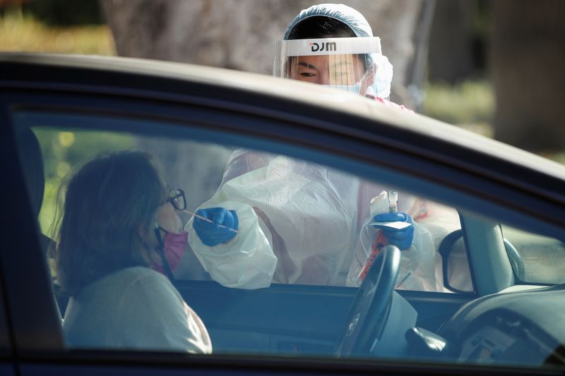 © Reuters. FILE PHOTO:  A healthcare worker at LAC USC Medical Center tests a person at a drive through testing center during the outbreak of the coronavirus disease (COVID-19) in Los Angeles, California
