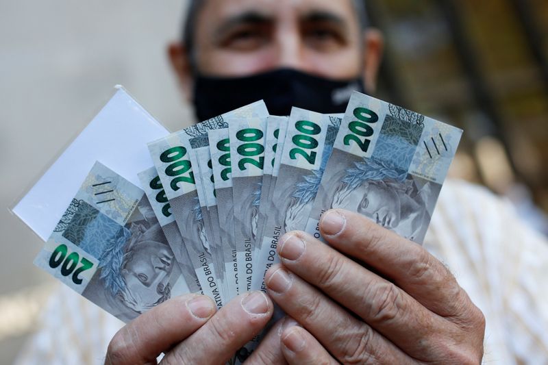 &copy; Reuters. Homem segura notas de 200 reais após o lançamento da nova cédula, em Brasília