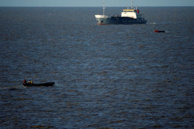 &copy; Reuters. FILE PHOTO: Small fishing boats pass in front of a cargo ship in Georgetown