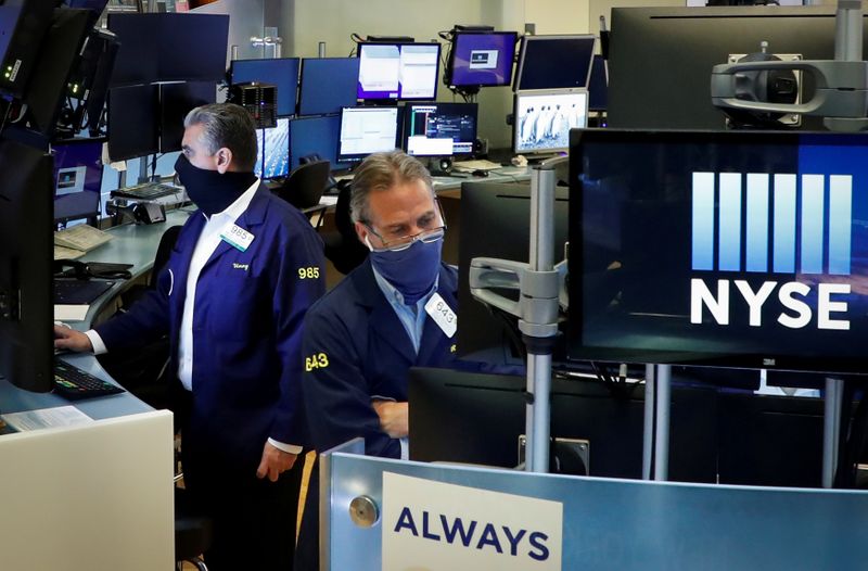 © Reuters. FILE PHOTO: Traders wearing masks work, on the first day of in person trading since the closure during the outbreak of the coronavirus disease (COVID-19) on the floor at the NYSE in New York