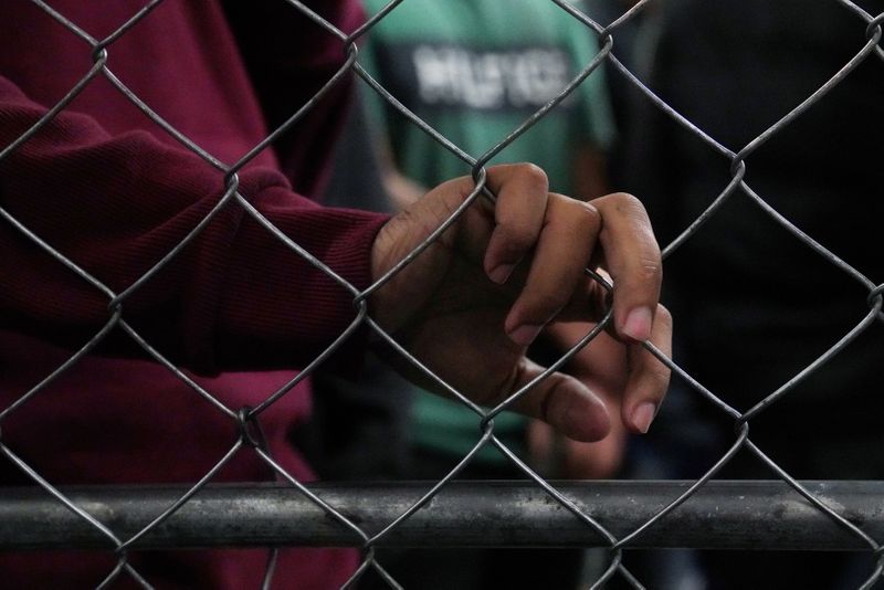 © Reuters. FILE PHOTO: Single-adult male detainees wait along a fence inside a Border Patrol station in McAllen, Texas