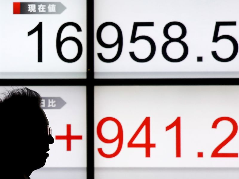 &copy; Reuters. A man walks past an electronic board showing Japan&apos;s Nikkei average outside a brokerage in Tokyo