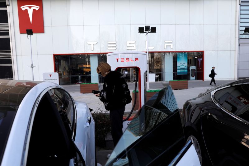 &copy; Reuters. FILE PHOTO: Woman charges a Tesla car in front of the electric vehicle maker&apos;s showroom in Beijing