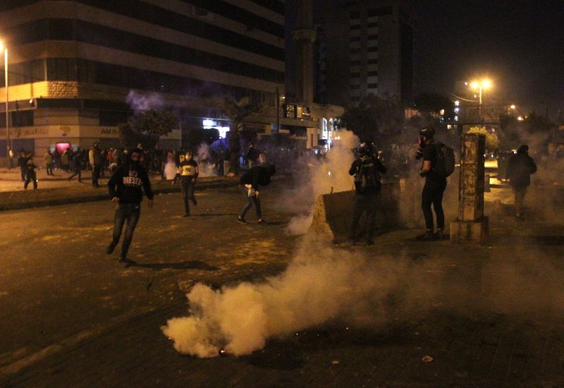 &copy; Reuters. Demonstrators are pictured near smoke rising from tear gas during a protest against the lockdown and worsening economic conditions, amid the spread of the coronavirus disease (COVID-19), in Tripoli