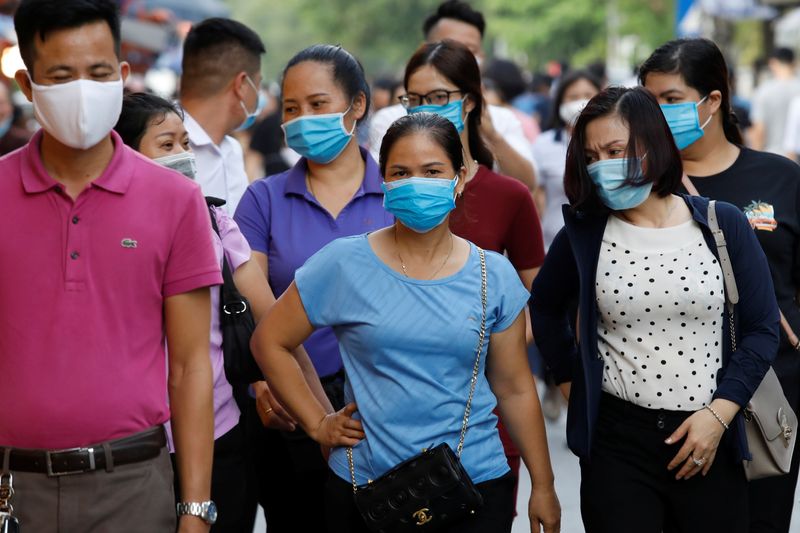 &copy; Reuters. FILE PHOTO: Pilgrims wear protective masks as they go to a temple on the first day of the month-long festival of the hungry ghosts in Hanoi