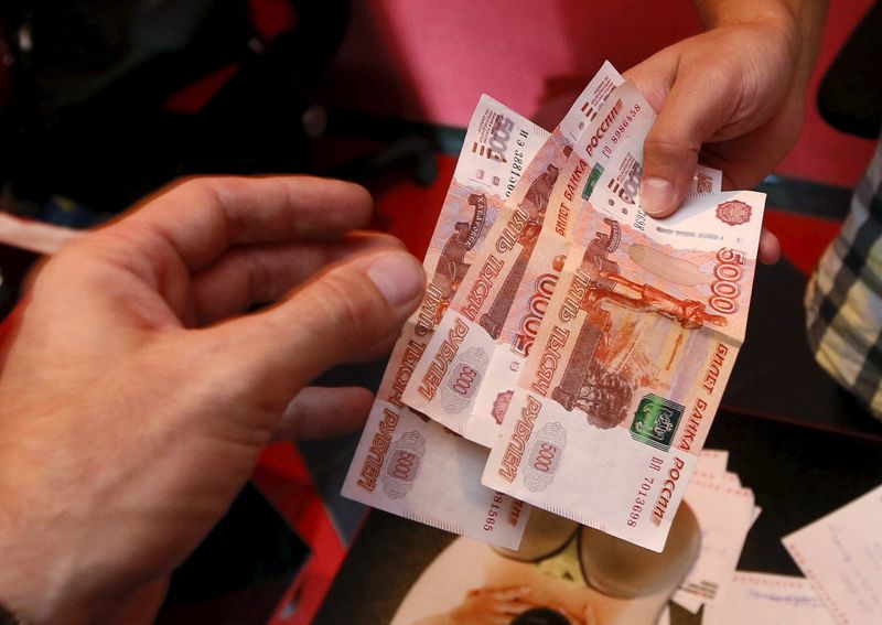 &copy; Reuters. An employee of a car service station takes Russian rouble banknotes from a client in Krasnoyarsk