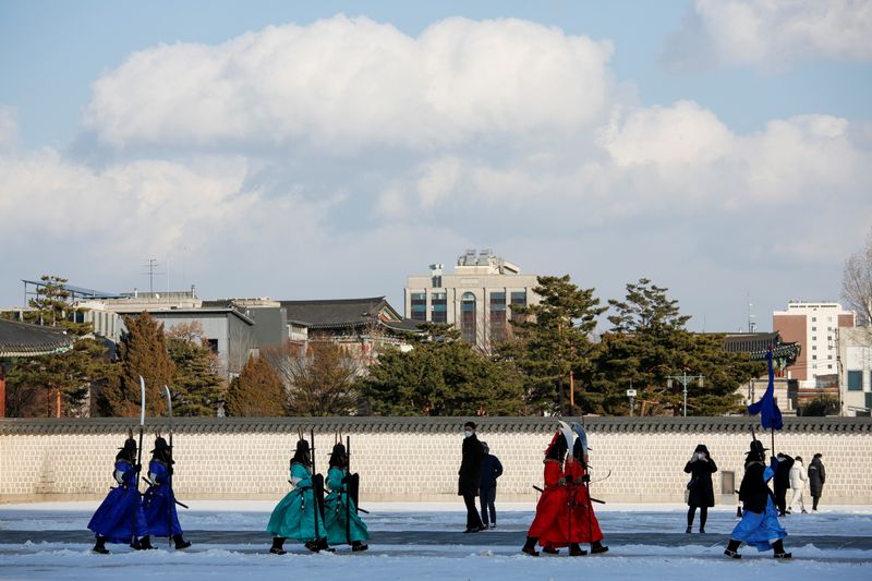 &copy; Reuters. Workers wearing traditional attire walk on a cold winter day, amid the coronavirus disease (COVID-19) pandemic during the daily re-enactment of the changing of the Royal Guards at Gyeongbok Palace in central Seoul