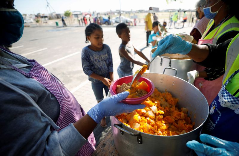 © Reuters. FILE PHOTO: Children queue for food at a school feeding scheme during a nationwide lockdown aimed at limiting the spread of the coronavirus disease (COVID-19) in Blue Downs township near Cape Town