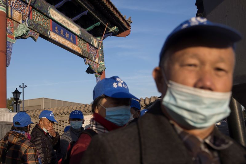 &copy; Reuters. Imagen de archivo de personas con mascarillas cerca de un centro turístico en Pekín, China.