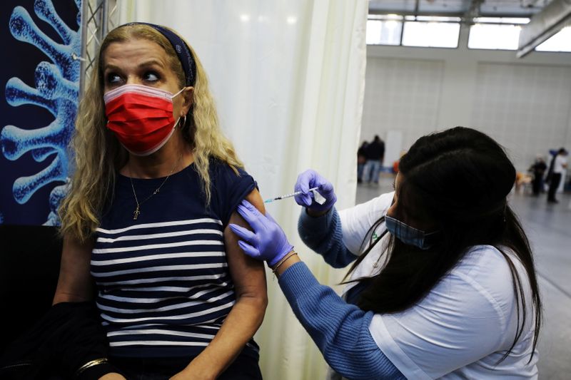 © Reuters. A woman receives a vaccination against the coronavirus disease (COVID-19) at a temporary Clalit healthcare maintenance organisation (HMO) centre, at a basketball court in Petah Tikva