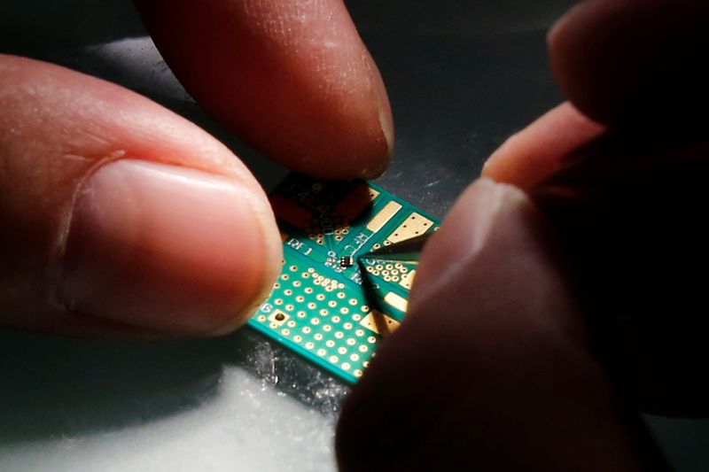 &copy; Reuters. A researcher plants a semiconductor on an interface board during a research work to design and develop a semiconductor product at Tsinghua Unigroup research centre in Beijing