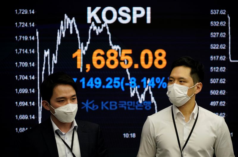 &copy; Reuters. FOTO DE ARCHIVO. Operadores bursátiles pasan junto a un tablero electrónico que muestra el índice de precios de las acciones de Corea (KOSPI) en una sala de operaciones de un banco en Seúl, Corea del Sur