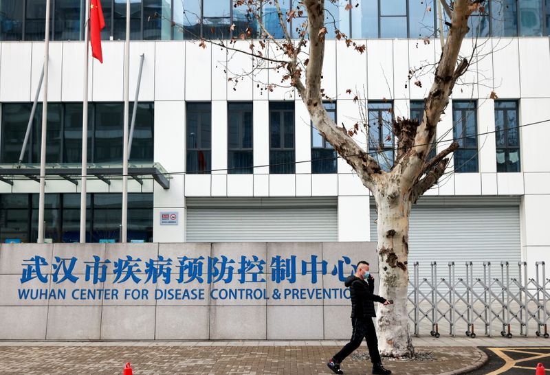 &copy; Reuters. Foto del lunes de un hombre con mascarilla pasando frente a la sede del CDC de Wuhan, en China