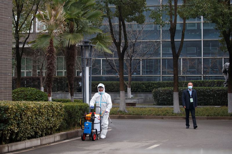 &copy; Reuters. Funcionário com traje de proteção desinfecta pavimento antes de chegada de equipe da OMS a centro de prevenção de doenças animais em Wuhan