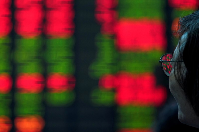 &copy; Reuters. Un investitore osserva un tabellone elettronico nei pressi del distretto finanziario di Shanghai