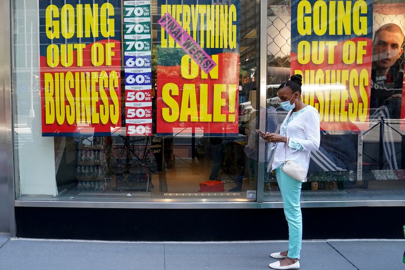 © Reuters. FOTO DE ARCHIVO: Personas pasan frente a un negocio que está cerrando tras el brote de la enfermedad del coronavirus (COVID-19) en el distrito de Manhattan de la ciudad de Nueva York.