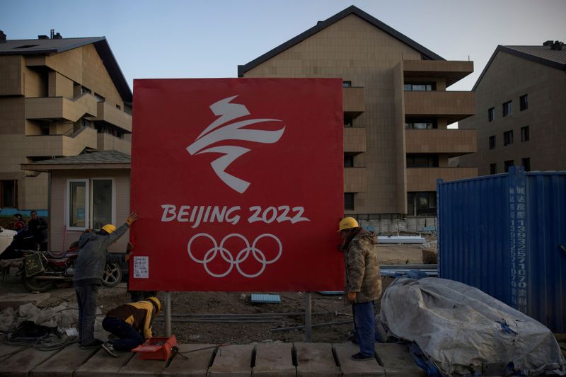 &copy; Reuters. FILE PHOTO: Workers move a sign at the Olympic Village in the Chongli district of Zhangjiakou