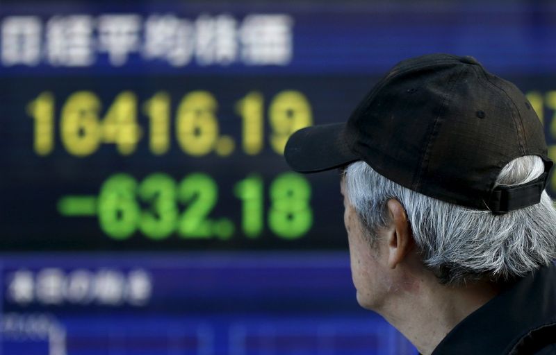 &copy; Reuters. A man walks past an electronic board showing Japan&apos;s Nikkei average outside a brokerage in Tokyo