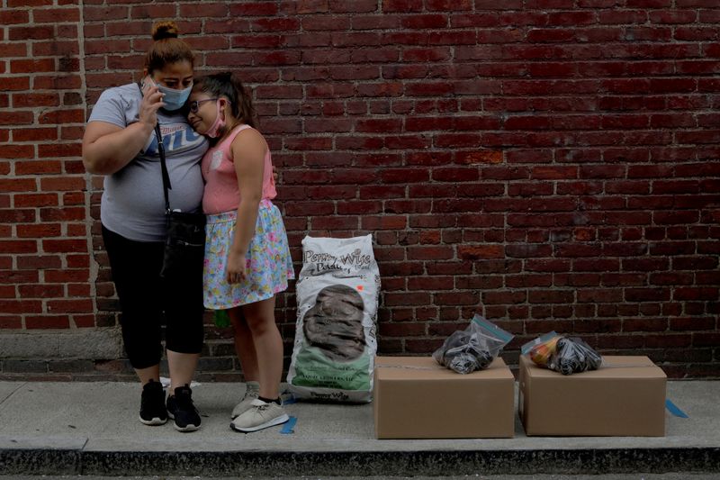 &copy; Reuters. Cidadã norte-americana desempregada e sua filha aguardam carona após receberem alimentos gratuitos de instituição em Massachusetts, nos EUA