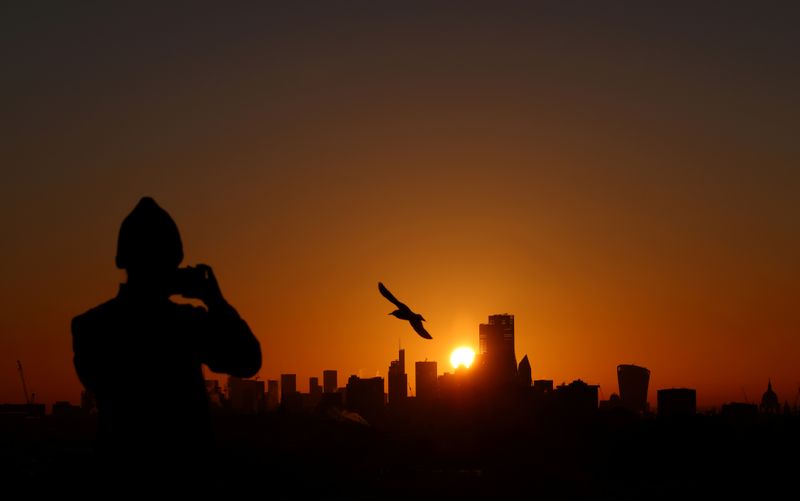 © Reuters. FILE PHOTO: A person takes a photograph of the London skyline from Primrose Hill
