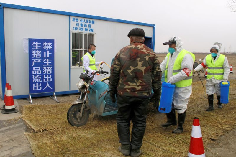 &copy; Reuters. FILE PHOTO: Workers disinfect a vehicle at a checkpoint on a road leading to a farm where African swine fever was detected in Xushui