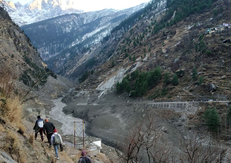 © Reuters. People walk past a destroyed dam after a Himalayan glacier broke and crashed into the dam at Raini Chak Lata