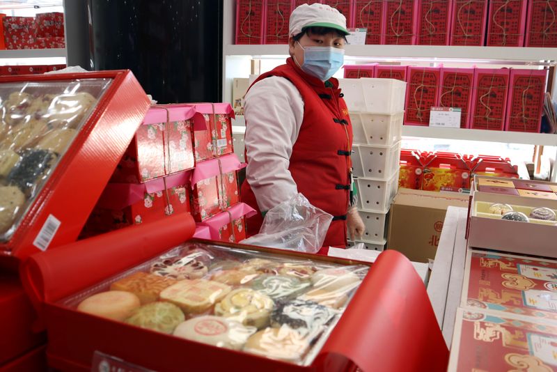 &copy; Reuters. Staff member stands behind Lunar New Year gift sets at a food store in Beijing