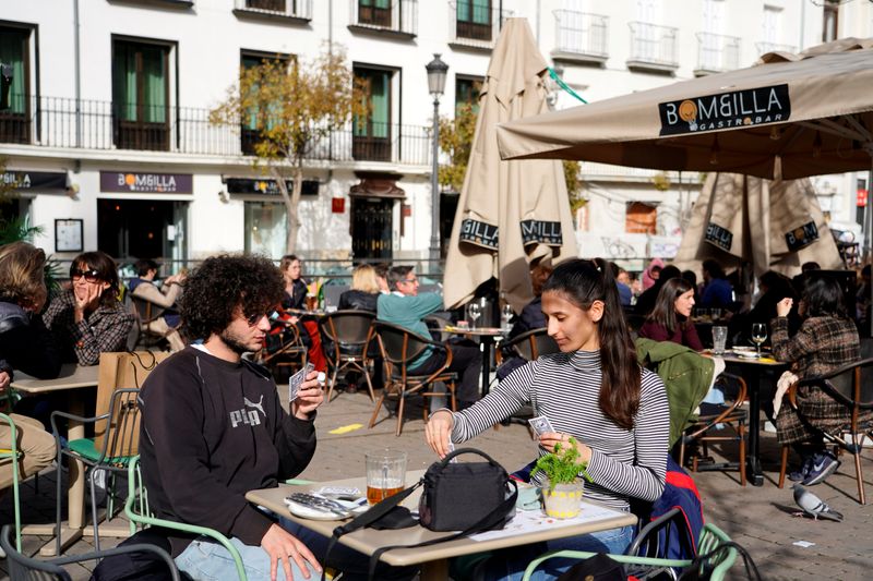 &copy; Reuters. Los visitantes franceses Theo Perucci y su hermana Luna juegan a las cartas mientras disfrutan de una comida en una terraza en Madrid, España, 5 de febrero de 2021