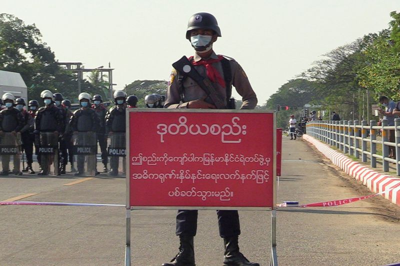 &copy; Reuters. Foto del lunes de un policía detrás de un cartel que advierte a los manifestantes de que no avancen, en Naypyitaw, capital de Myanmar