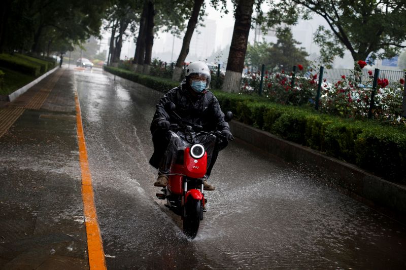&copy; Reuters. FILE PHOTO: A man rides a Niu electric scooter through a puddle as a sudden thunderstorm darkens the mid-afternoon sky in Beijing