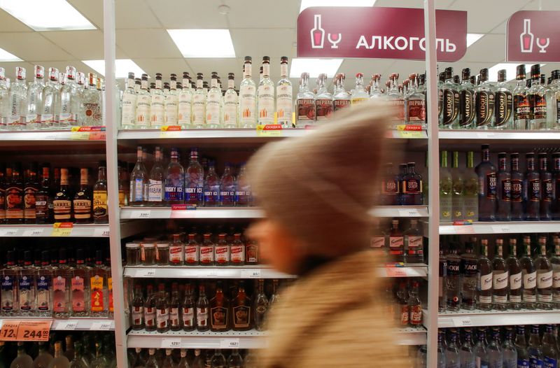 © Reuters. A customer walks past shelves with bottles of vodka in a supermarket in Moscow