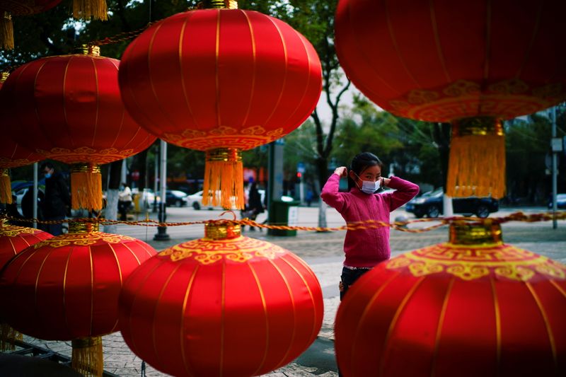 &copy; Reuters. A girl wearing a face mask walks on a street decorated for Lunar New Year celebrations, following an outbreak of the coronavirus disease (COVID-19) in Wuhan