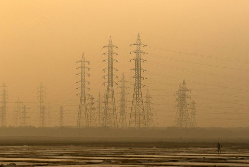 &copy; Reuters. A worker levels a salt pan near electricity pylons in Mumbai