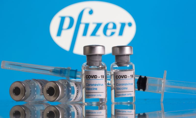 &copy; Reuters. Vials labelled &quot;COVID-19 Coronavirus Vaccine&quot; and sryinge are seen in front of displayed Pfizer logo in this illustration