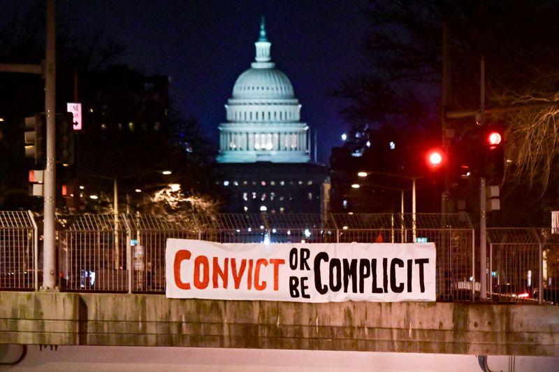 &copy; Reuters. A banner reading, &quot;Convict or be complicit&quot; is hung over a bridge in view of the U.S. Capitol on the first day of the Senate impeachment trial against former President Donald Trump in Washington