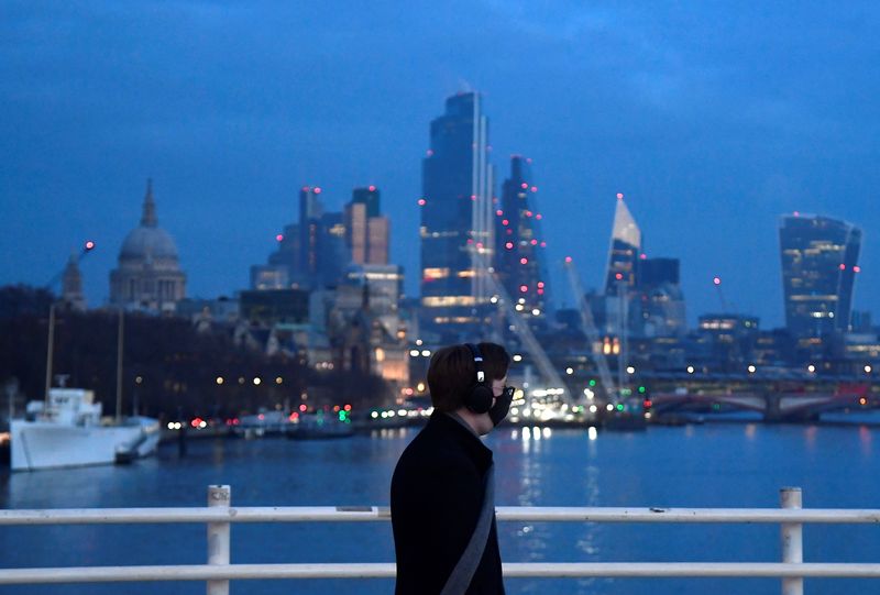 &copy; Reuters. A man looks towards skyscrapers of the City of London financial district as he crosses Waterloo Bridge in London