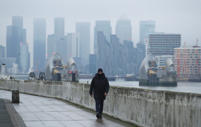 &copy; Reuters. Buildings are seen in the Canary Wharf business district, as a man walks along a footpath, amid the outbreak of the coronavirus disease (COVID-19), in London
