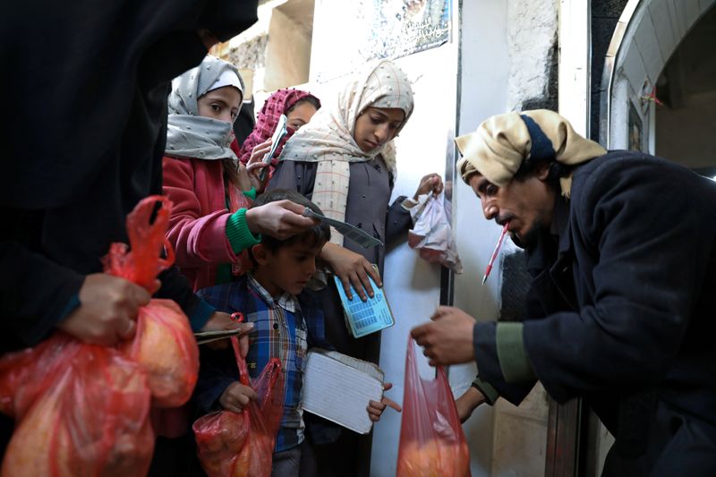 &copy; Reuters. FILE PHOTO: A woman and children receive food donations from a charity kitchen in Sanaa, Yemen