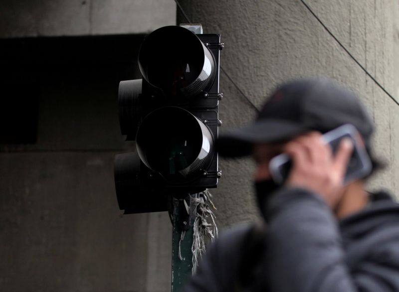 &copy; Reuters. Una persona habla por su móvil con un semáforo de fondo durante un corte de electricidad en Monterrey, México