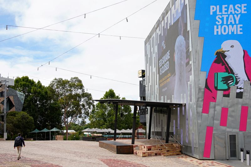 &copy; Reuters. A man walks past a &apos;Please Stay Home&apos; sign on the first day of a five-day COVID-19 lockdown in Melbourne