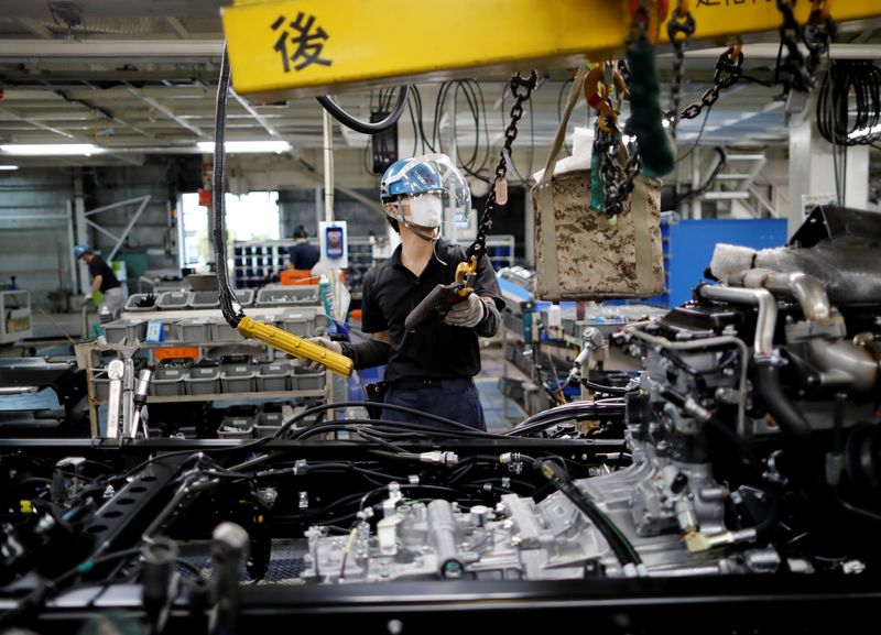 &copy; Reuters. FILE PHOTO: An employee wearing a protective face mask and face guard works on the automobile assembly line at the factory of Mitsubishi Fuso Truck and Bus Corp in Kawasaki