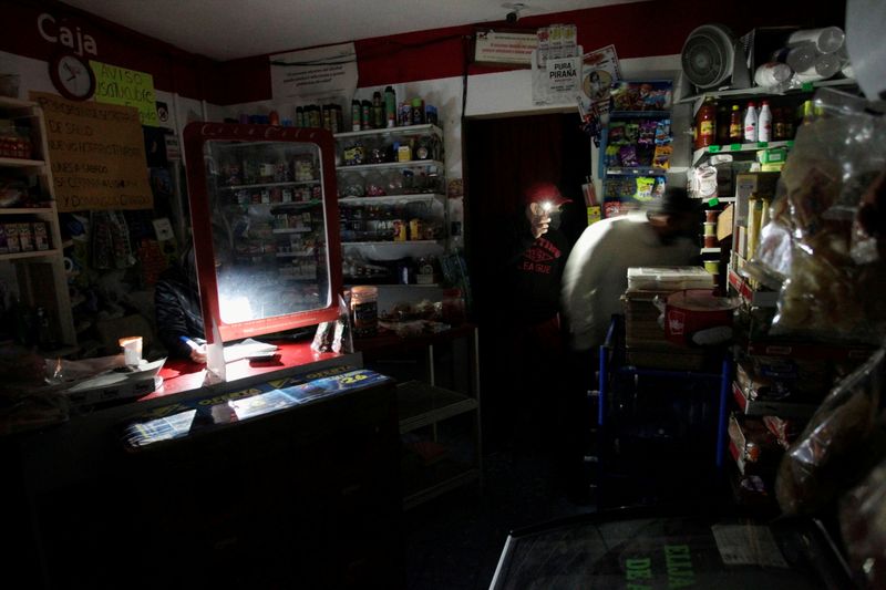 &copy; Reuters. FILE PHOTO: A grocery store owner uses his cell phone flashlight to help a customer shopping in the dark during an electrical outage in Monterrey
